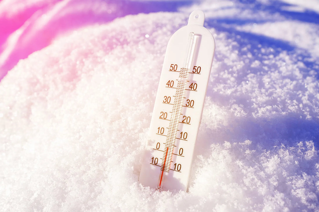 Outdoor thermometer partially buried in snow showing freezing temperatures, symbolizing sudden cold exposure and environmental temperature stress on the body and brain.